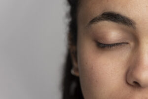 Sobrancelha natural em close, com olho fechado, revelando linhas suaves que sustentam o olhar e contribuem para a harmonia do rosto.