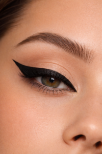 Close no olho com delineado preto preciso e elegante, pele natural e sombra suave em tons neutros.