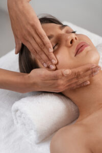 Pessoa recebendo massagem facial relaxante, com movimentos suaves nas laterais do rosto.