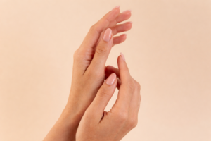 Mãos femininas com unhas naturais bem cuidadas em gesto suave, transmitindo delicadeza, autocuidado e beleza minimalista.