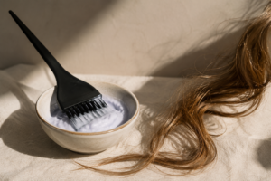 Recipiente com mistura para limpeza de fios ao lado de mechas de cabelo iluminadas por luz natural suave.