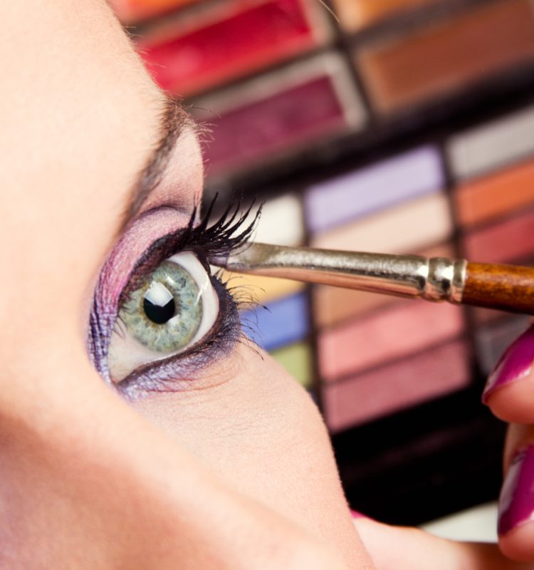 Mulher aplicando maquiagem esfumada com sombras vibrantes em tons de rosa e roxo nos olhos