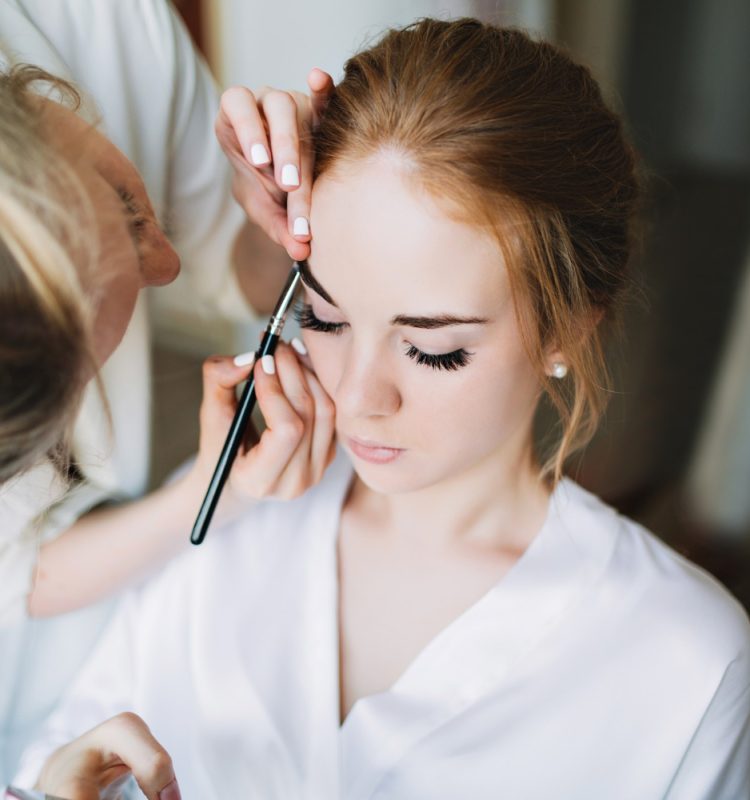 "Maquiadora profissional aplicando maquiagem delicada em noiva, preparando um look natural e duradouro para o dia do casamento."