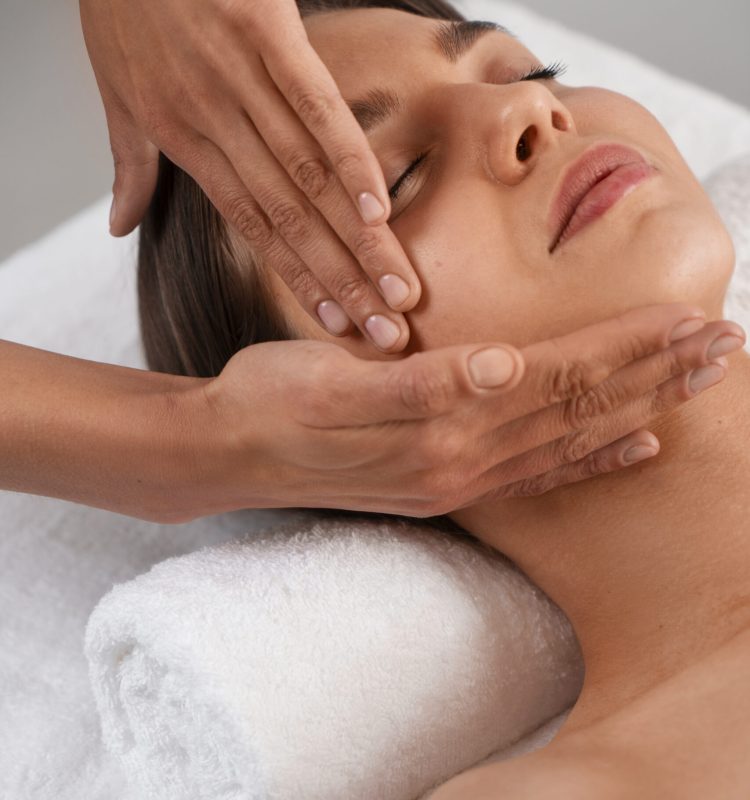 Pessoa recebendo massagem facial relaxante, com movimentos suaves nas laterais do rosto.